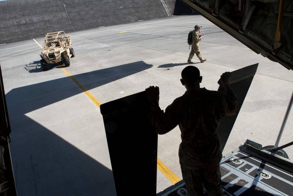 U.S. Air Force Airmen from the 17th Special Operations Squadron prepare to load a vehicle onto a MC-130J Commando II as part of a mass launch training mission June 22, 2017, at Kadena Air Base, Japan. Routine flights and airdrops are conducted to maintain proficiency and training certifications for prospective missions. (U.S. Air Force photo by Senior Airman John Linzmeier)