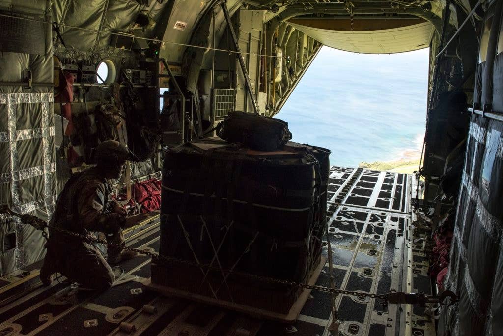 A U.S. Air Force loadmaster from the 17th Special Operations Squadron prepares to airdrop a package onto Le Shima Range, Okinawa, Japan, during a mass launch training mission June 22, 2017. Aircrews must consider a number of variables in order to execute a precise and effective airdrop, to include wind speed, aircraft velocity, altitude, location and timing. (U.S. Air Force photo by Senior Airman John Linzmeier)