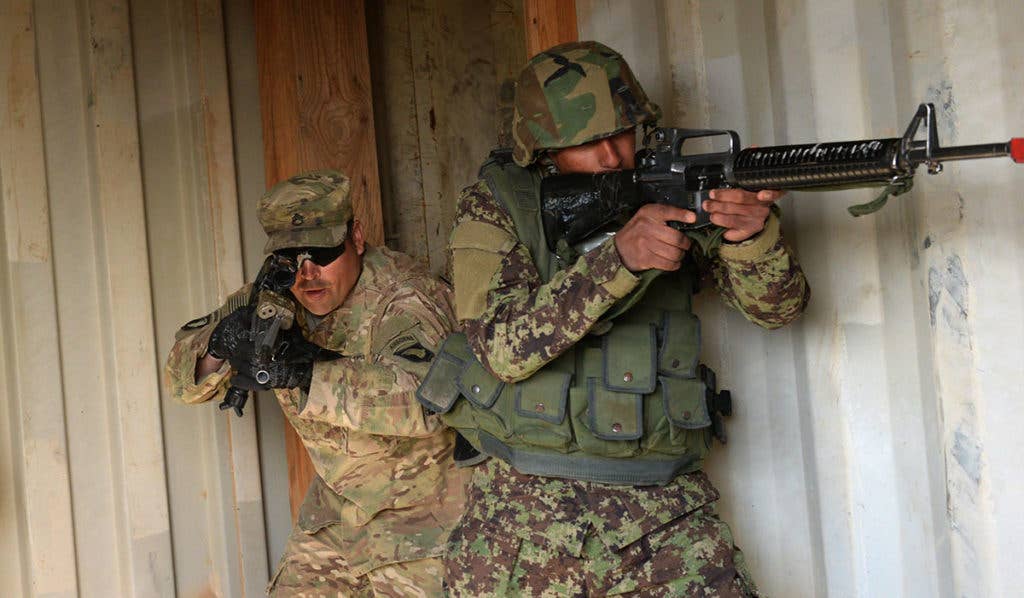 A U.S. Army adviser from Task Force Forge conducts a room clearing drill with an Afghan trainee. (NATO photo by Kay M. Nissen)