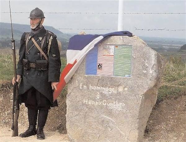 A man in WWI-era French uniform stands beside a memorial stone at the spot where Henry Gunther fell on Nov. 11, 1918. The stone was unveiled by the French government as part of a 90th anniversary event in 2008. (Photo by American War Memorials Overseas)