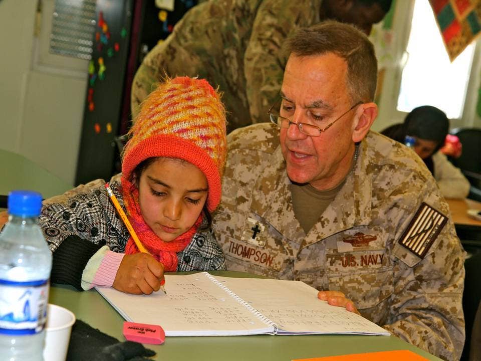 A U.S. Navy chaplain, right, studies English with an Afghan girl during a volunteer session May 27, 2013, at the Cat in the Hat Language Arts Center at Bagram Airfield, Afghanistan. (DoD photo by Erica Fouche, U.S. Army)
