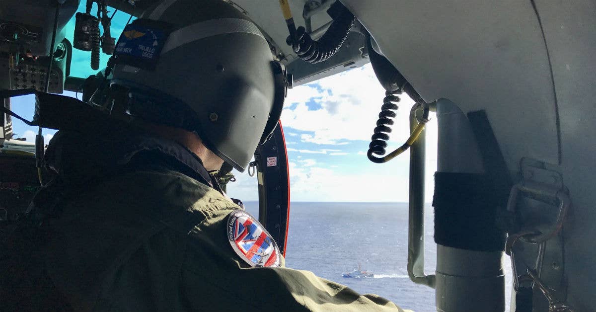 An aircrewman aboard a Coast Guard MH-65 Dolphin helicopter from Air Station Barbers Point scans the waters off Oahu Aug. 18, 2017, for any sign of five missing aviators from an Army UH-60 Black Hawk helicopter. USCG photo by Air Station Barbers Point.