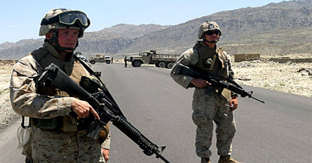 These Marines stand close by one another as they conduct a vehicle checkpoint in Afghanistan. (Source: Wikipedia Commons)