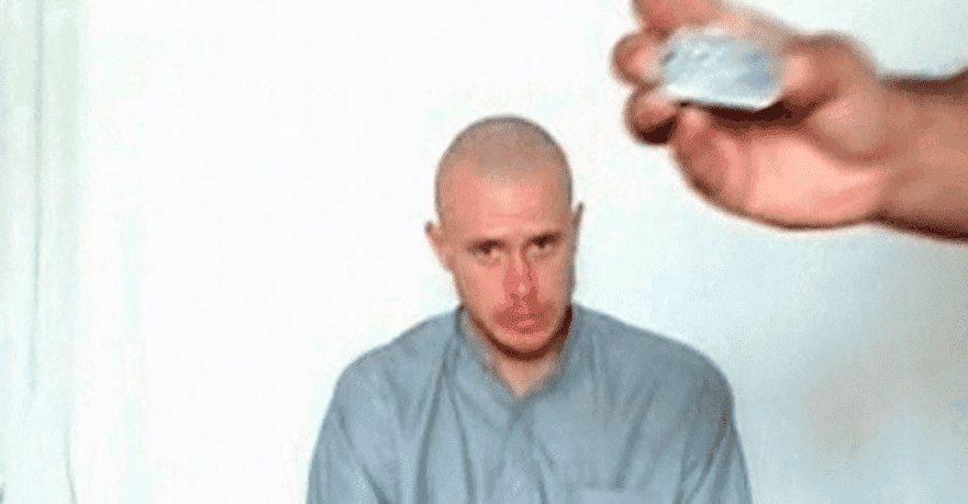 Bowe Bergdahl watches as one of his captors displays his identity tag in this still from a Taliban-released video.