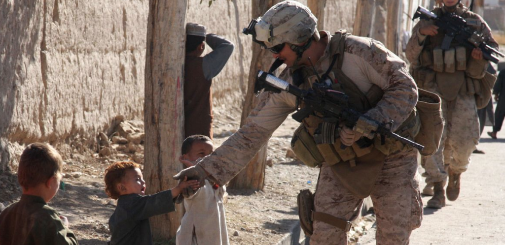 Doc Silva handshakes the hand of a few Afghan children while on patrol. (Image from Wikipedia Commons)