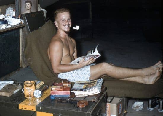 Airman 2nd Class Bob 'Red' Cunningham, 1374th Mapping and Charting Squadron, sits near his footlocker and reads a magazine during his six-month assignment on North Danger Island in 1956. The 22-year old radar operator and his three teammates lived in a tent and shared the tiny island in the South China Sea with a six-man Air Force radio relay station team. (Courtesy photo Bob Cunningham)