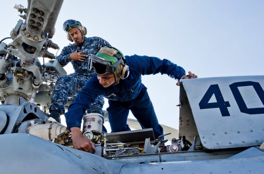 Aviation Electronics Mate Airman Adam Lowery (front) and Aviation Electronics Technician Airman Tyler Humphries (back) conduct routine maintenance on an MH-60S Sea Hawk assigned to the Merlins of Helicopter Sea Combat Squadron (HSC) 3. (U.S. Navy photo by Mass Communication Specialist 2nd Class Jesse L. Gonzalez).