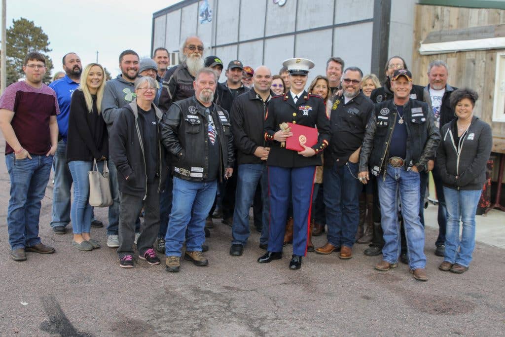 Sergeant Sara McGaffee, a Sioux Falls, S.D., native, poses for a photo with the Marines of Recruiting Sub Station Sioux Falls after being awarded the Purple Heart Medal. On Oct. 20th, 2010, while deployed with Combat Logistics Battalion 3, McGaffee's vehicle was hit by an improvised explosive device while conducting convoy operations in support of Operation Steel Dawn II in the Helmand province of Afghanistan. McGaffee was awarded her Purple Heart, Dec. 16, 2017 in Sioux Falls, S.D., in front of a detail of Marines and her local friends and family. (Image Sgt. Michelle Reif)