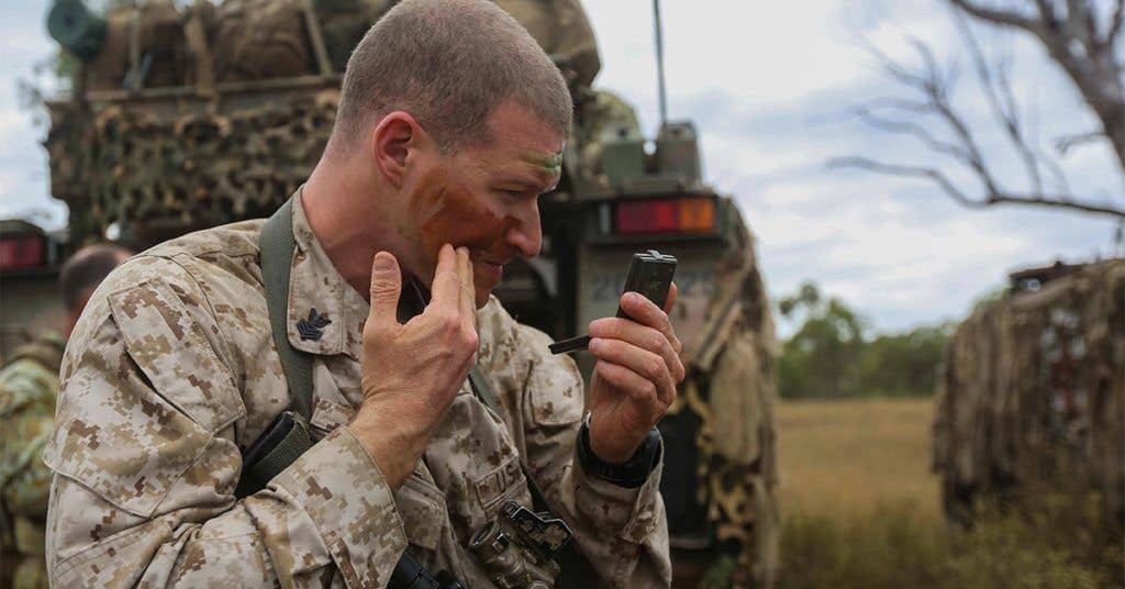 U.S. Navy Hospital Corpsman 1st Class Adam Zani, applies camo paint before heading out on a mission with the Marines. (Image from USMC)