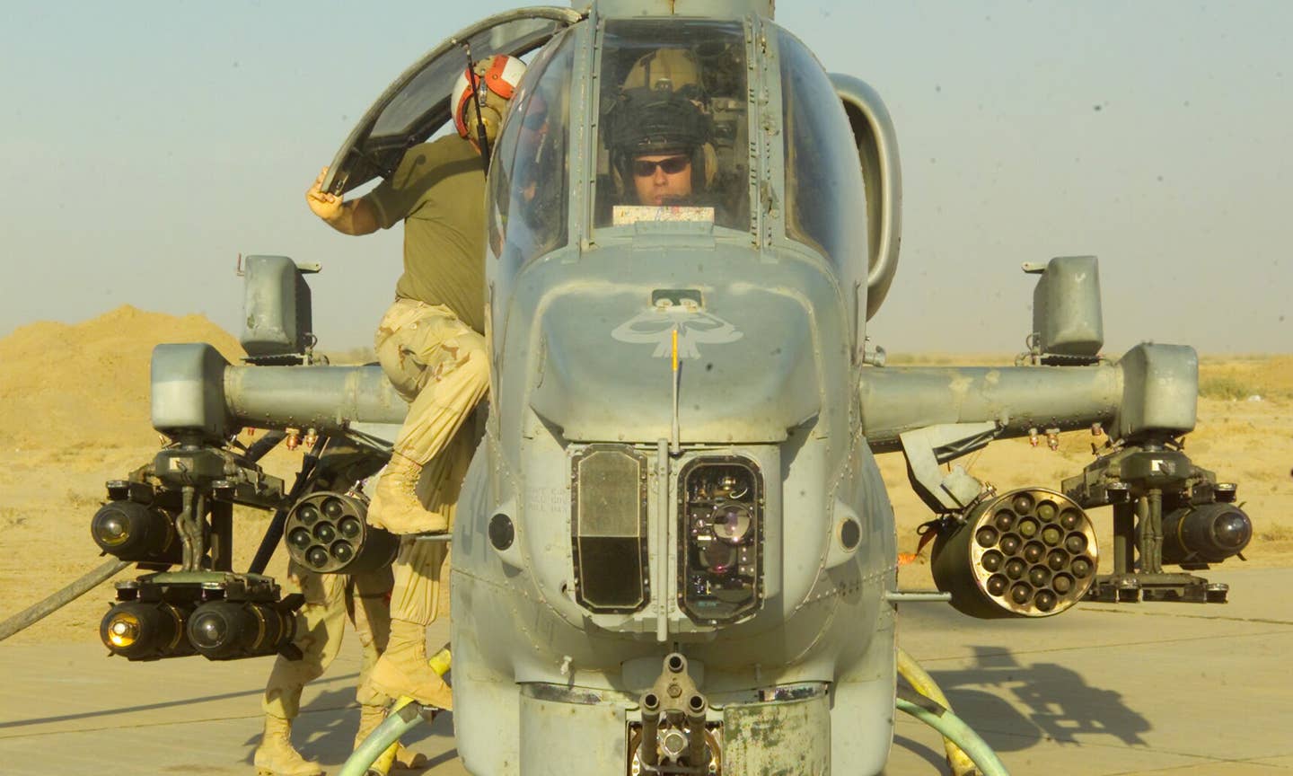 A Marine from Heavy Mobile Helicopter Squadron 169, speaks to the copilot of an AH-1 Cobra while refueling at a Forward Operating Base in Iraq April 11 while in support of Operation Iraqi Freedom. Operation Iraqi Freedom is the multinational coalition effort to liberate the Iraqi people, eliminate Iraq's weapons of mass destruction and end the regime of Saddam Hussein. (USMC photo by Lance Cpl. Jonathan P. Sotelo)