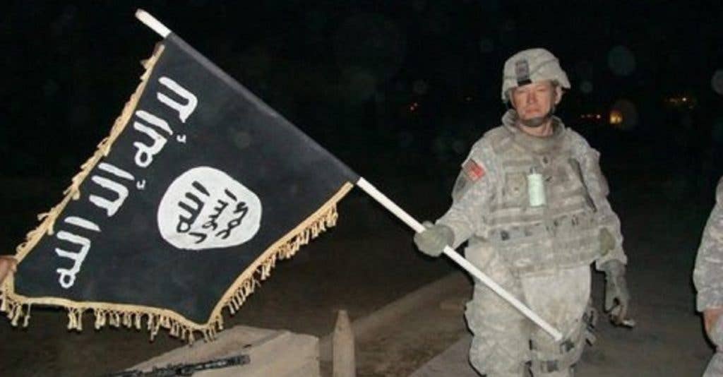 A soldier with the United States Army shows off a captured ISIS flag. (US Army photo)