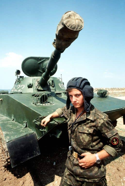 A Soviet naval infantryman (Marine) stands with an arm on his PT-76 light amphibious tank, on display for visiting Americans. North Vietnam used the PT-76 in the Vietnam War. (US Navy photo)