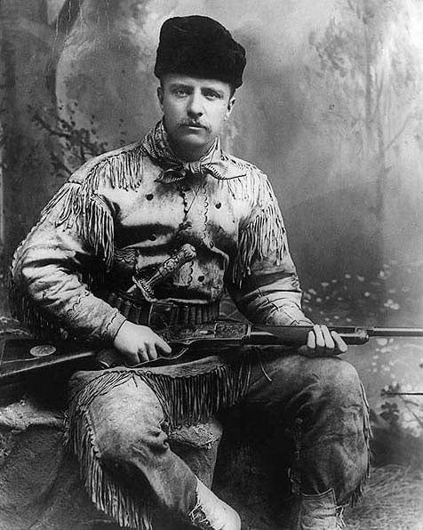 Theodore Roosevelt holding a Winchester rifle. The Winchester 1873 could fire the same round as the Colt Single-Action Army. (1885 photo by George Grantham Baine)