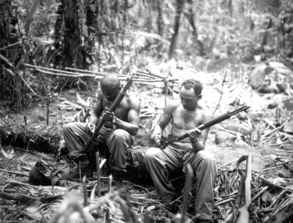 Two soldiers take time to clean their M1 Garand rifles on Bougainville. (US Army photo)