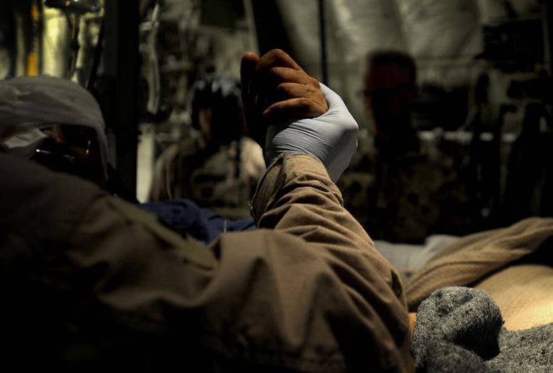 A medical tech holds the hand of a patient during an Aeromedical Evacuation mission transporting patients from Kandahar to Bagram Air Base.(U.S. Air Force Photo by Staff Sgt. Shawn Weismiller)