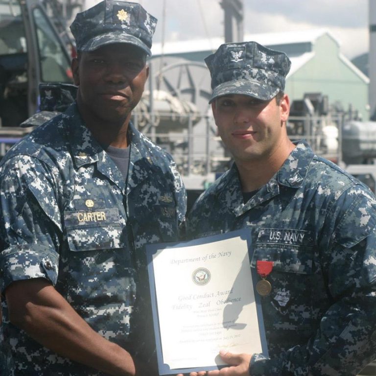 Travis Kirckof, pictured here receiving a Good Conduct Medal, spent hours in the water helping 46 of his shipmates to safety. (US Navy photo)