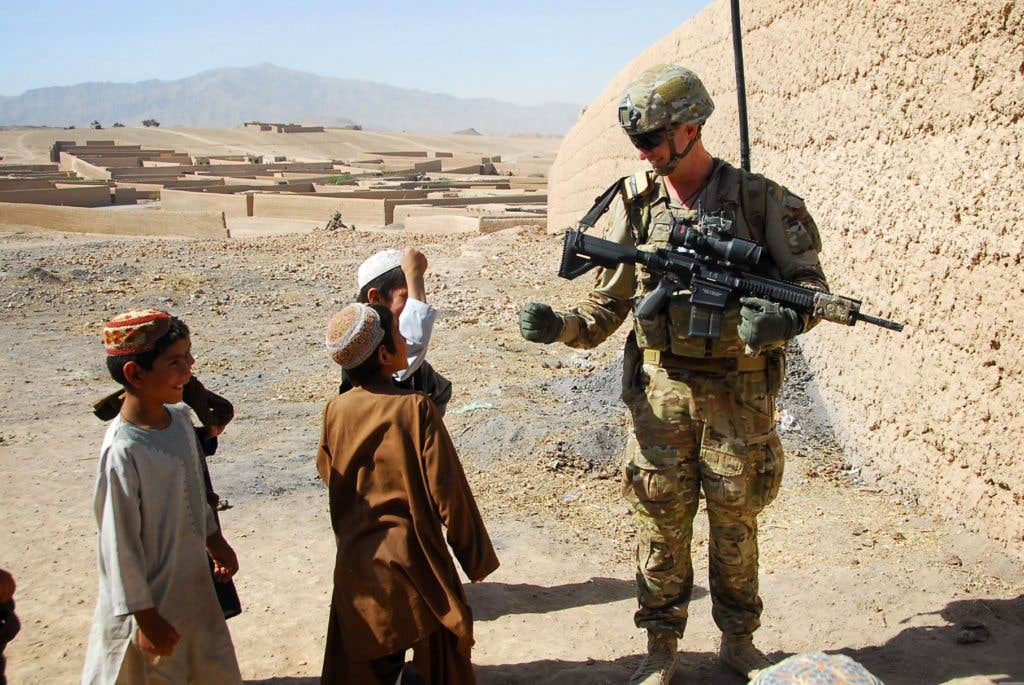 Australian Army Pvt. Levi Mooney, right, bumps fists with a child during a patrol in Tarin Kowt, Uruzgan province, Afghanistan, July 26, 2013. Mooney carries a HK417 rifle, similar to the M110A1 that will be the new squad-level designated marksman rifle. (U.S. Army National Guard photo by Sgt. Jessi Ann McCormick)