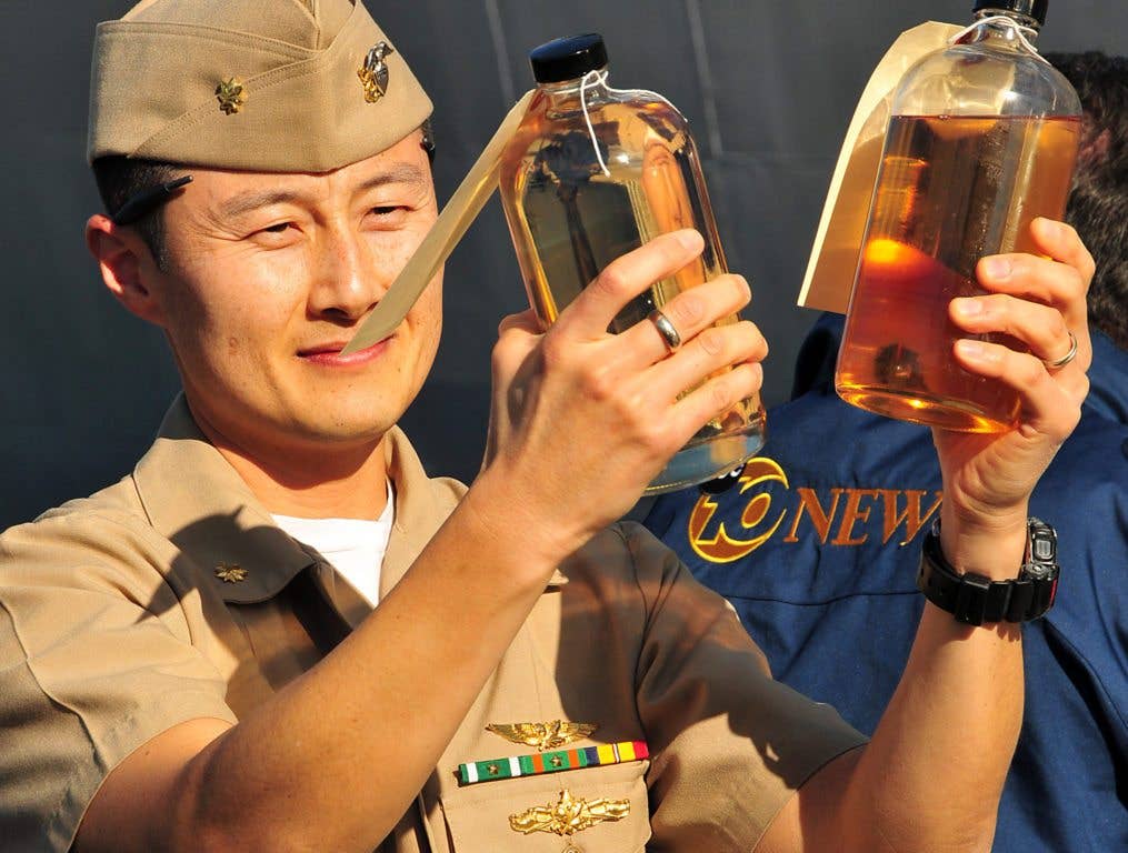 Lt. Cmdr. Frank Kim, fuel officer for Naval Supply Systems Command, Fleet Logistics Center San Diego, compares sample bottles of traditional diesel fuel marine and an algae-derived alternative fuel during the Navy's largest shipboard alternative fuel test at Naval Base Point Loma in San Diego. The biofuels proved to be very expensive. (U.S. Navy photo by Candice Villarreal)