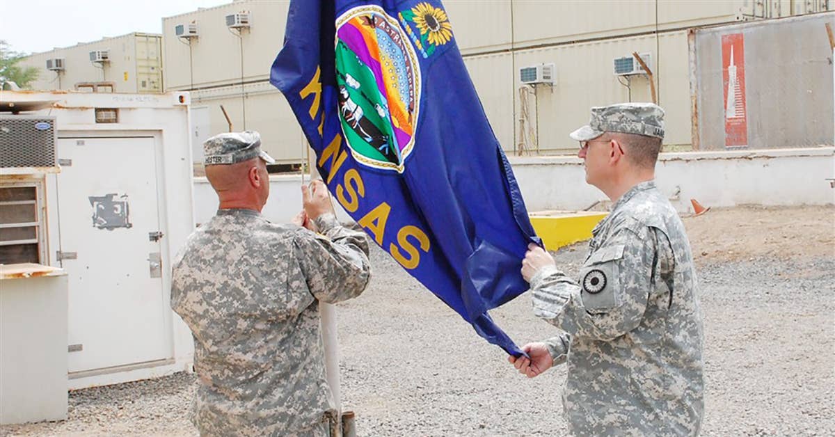 CAMP LEMONNIER, Djibouti - Soldiers assigned to the 2nd Combined Arms Battalion 137th Infantry Regiment, Kansas Army National Guard, hoist the Kansas state flag outside of the new battalion headquarters at Camp Lemonnier. (U.S. Navy photo by Petty Officer 1st Class Shawn D. Graham)