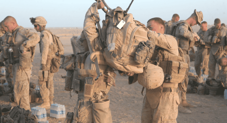 This Marine helps his brother-in-arm don his heavy pack before a mission. We hope he didn't forget anything.