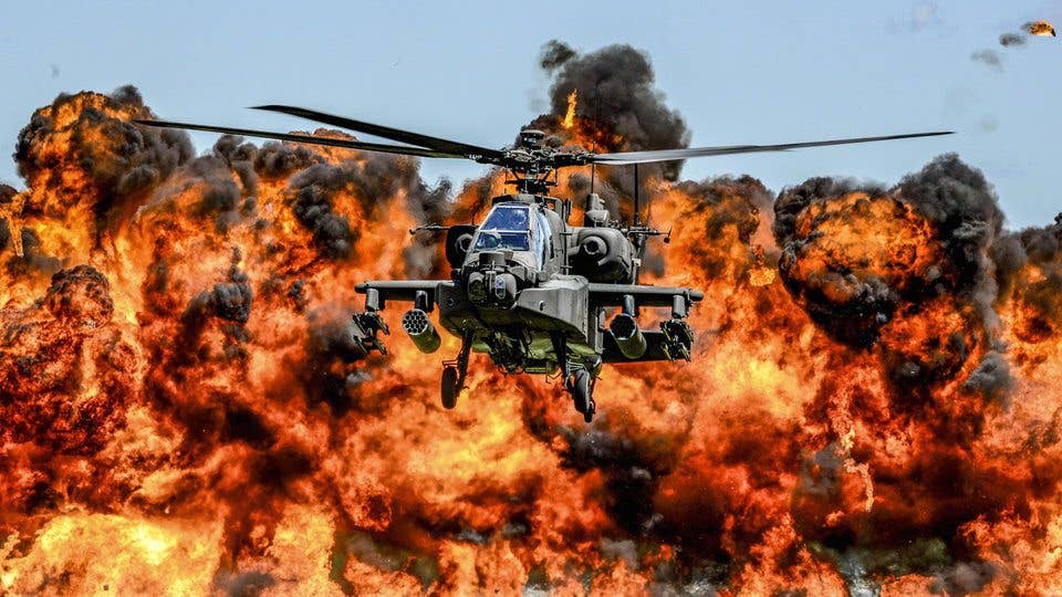 An AH-64D Apache attack helicopter flies in front of a wall of fire during the South Carolina National Guard Air and Ground Expo at McEntire Joint National Guard Base, South Carolina. (Photo by Air National Guard)