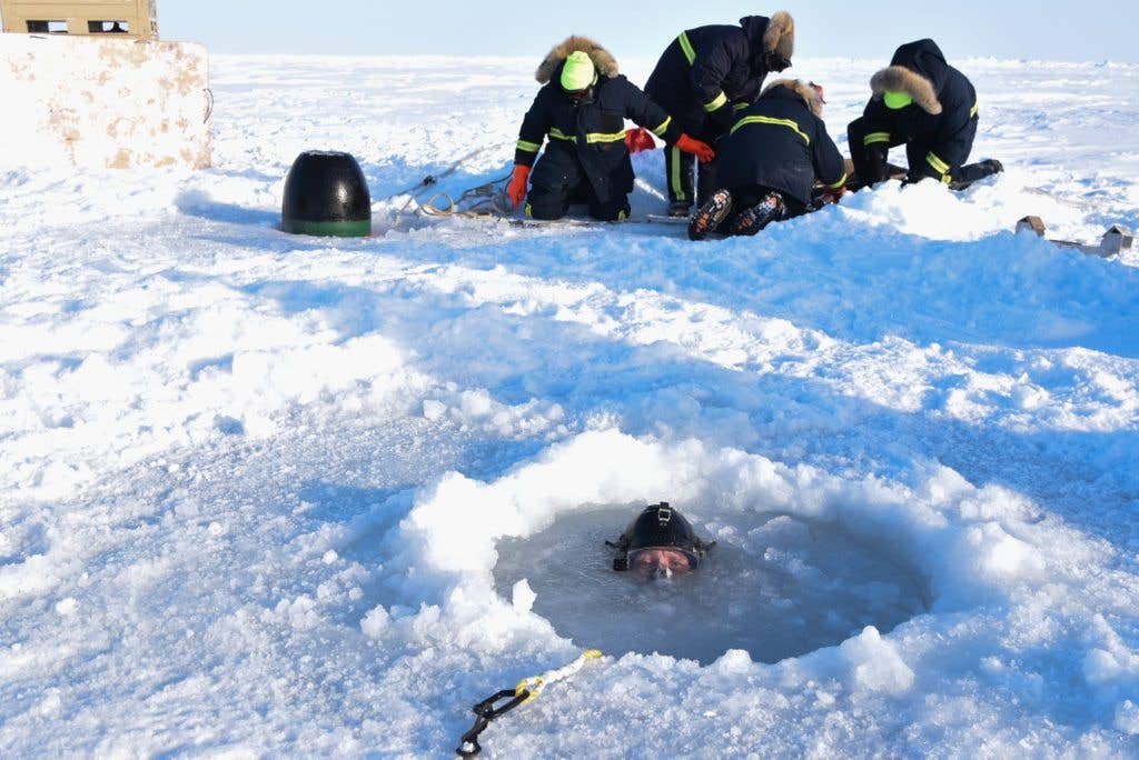 Chief Hospital Corpsman Kristopher Mandaro, assigned to Underwater Construction Team (UCT) 1, surfaces from a waterhole during a torpedo exercise in support of Ice Exercise (ICEX) 2018. (U.S. Navy photo by Mass Communication Specialist 1st Class Daniel Hinton)