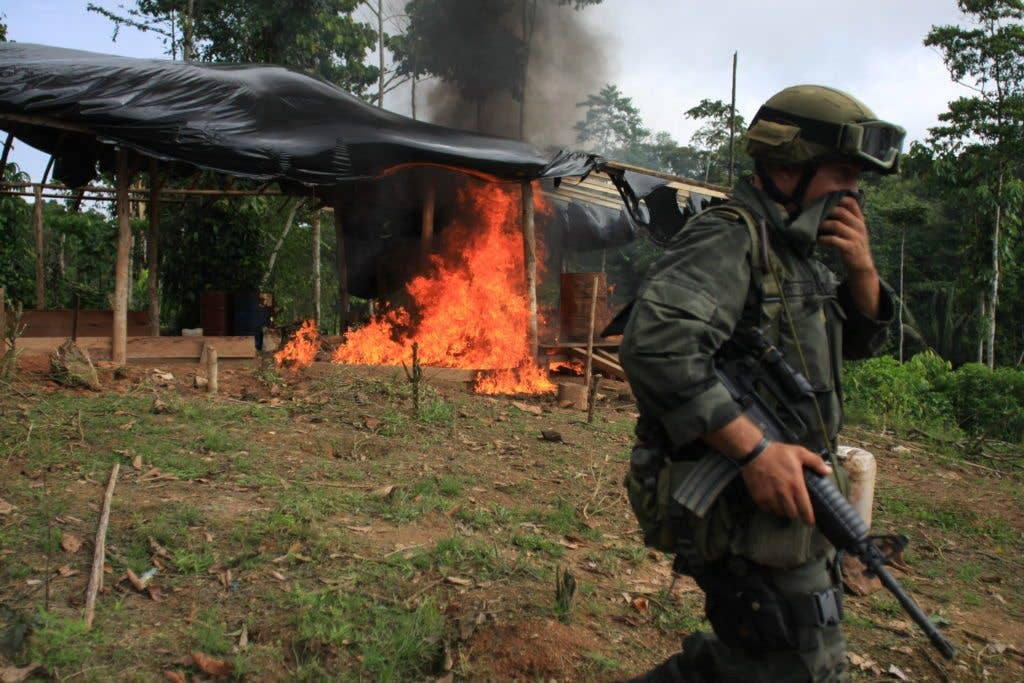 A member of an anti-narcotics police squad in front of a burning hut during a raid to destroy a coca laboratory near Tumaco, in southern Colombia, June 8, 2008. (Photo by William Fernando Martinez)