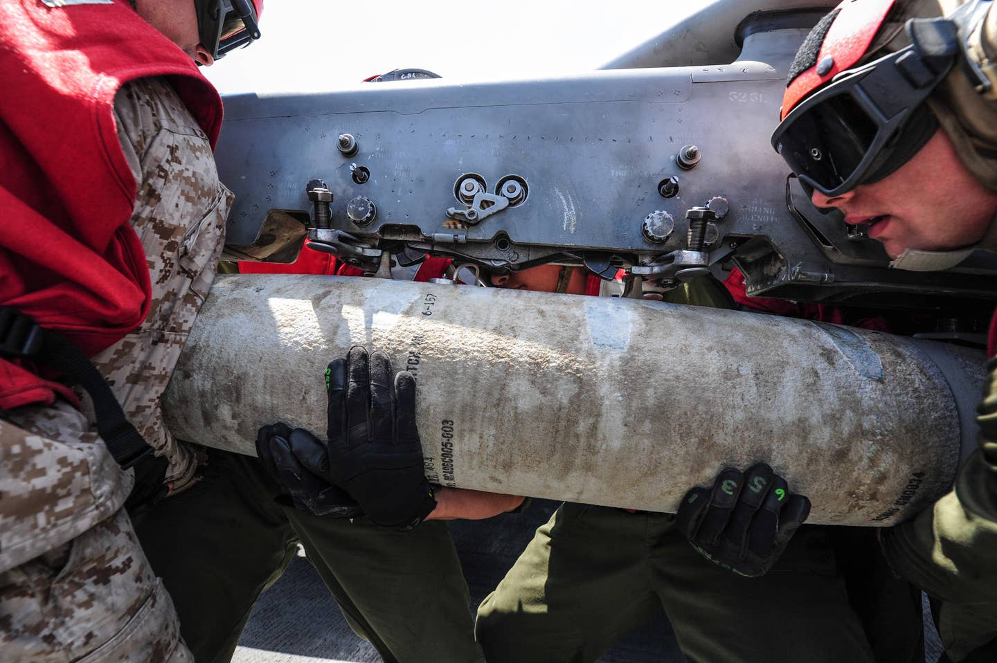Marines assigned to the 13th Marine Expeditionary Unit attach a Joint Direct Attack Munition (JDAM) to an AV-8B Harrier II.