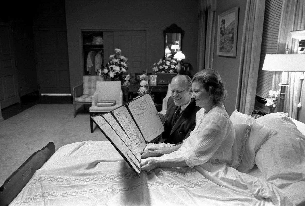 President Gerald Ford and First Lady Betty Ford read a petition, signed by all 100 members of the United States Senate, in the President's Suite at Bethesda Naval Hospital, Bethesda, MD, following the First Lady's breast cancer surgery, October 2, 1974.