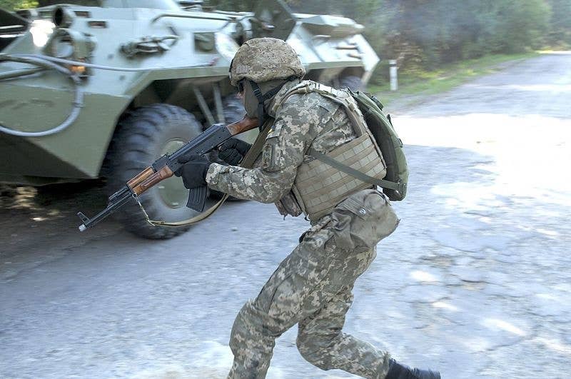 A Ukrainian soldier holding a weapon moves for cover during a training exercise