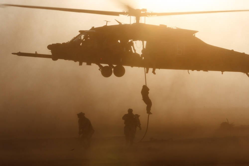 Night stalkers climbing a rope to a black hawk