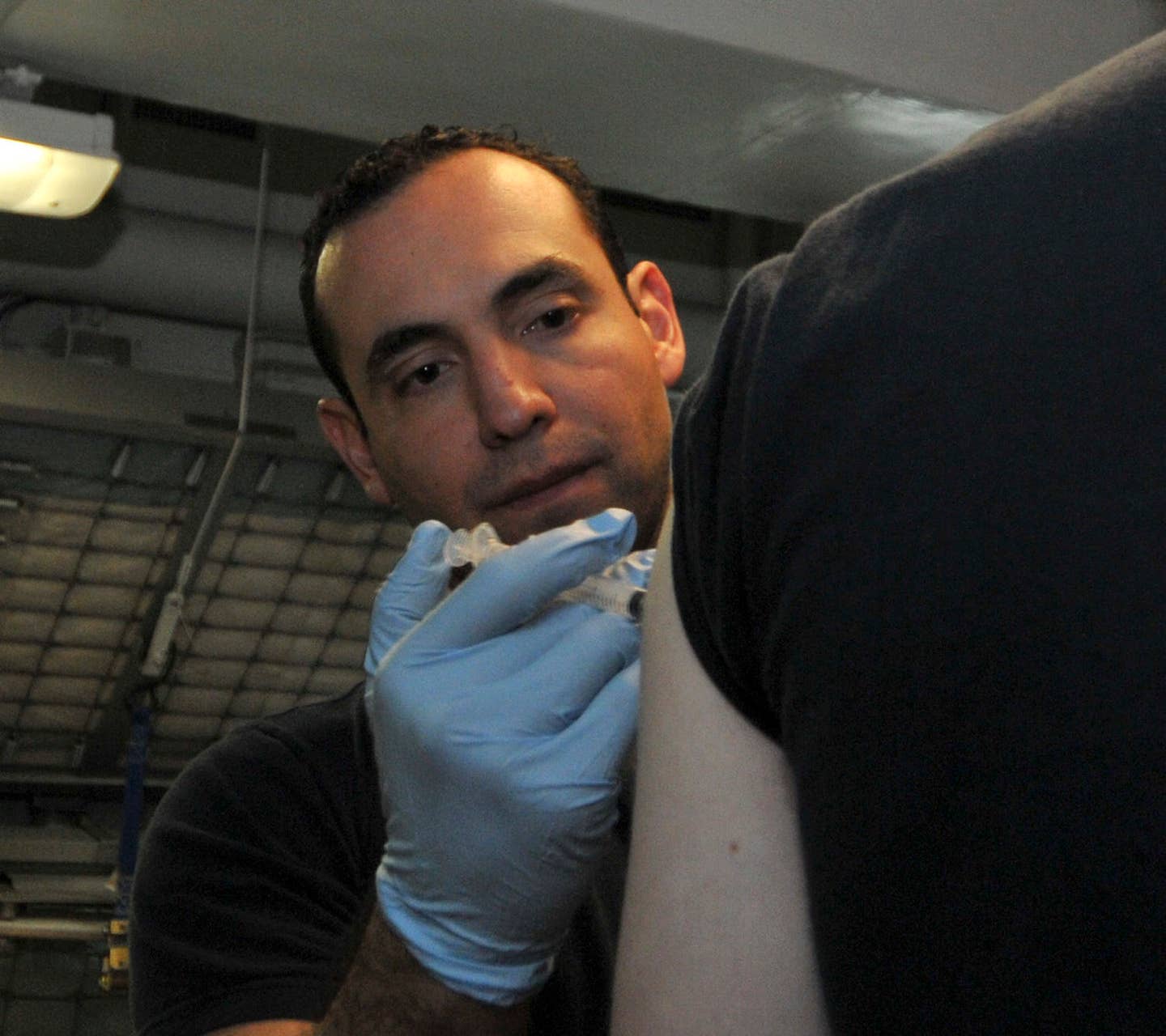 Hospital Corpsman 1st Class David Cano, from San Antonio, Texas, administers the anthrax vaccine to a Sailor.