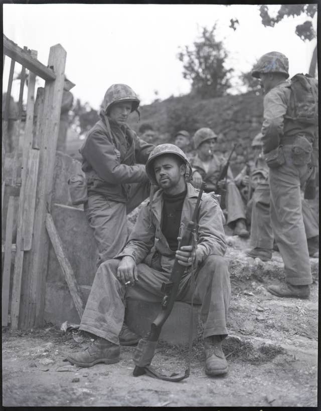 PFC. Urban Vachon of Laconia, NH, and Columnist Ernie Pyle, rest by the roadside on the trail at Okinawa.