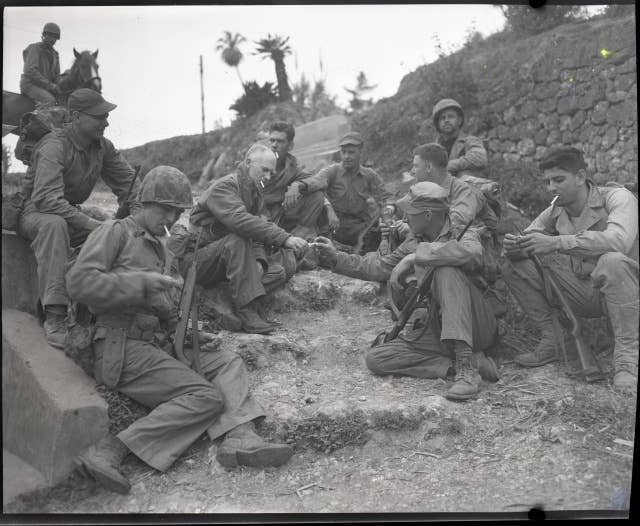 Columnist Ernie Pyle rests on the roadside with a Marine patrol.