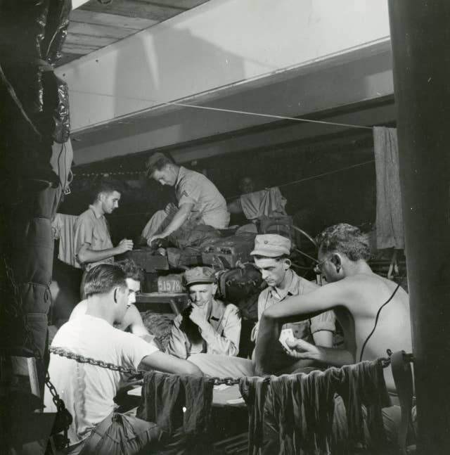 Ernie Pyle watching Marine play Casino aboard USS Charles Carroll (APA-28) while enroute to Okinawa / Date: March 29, 1945