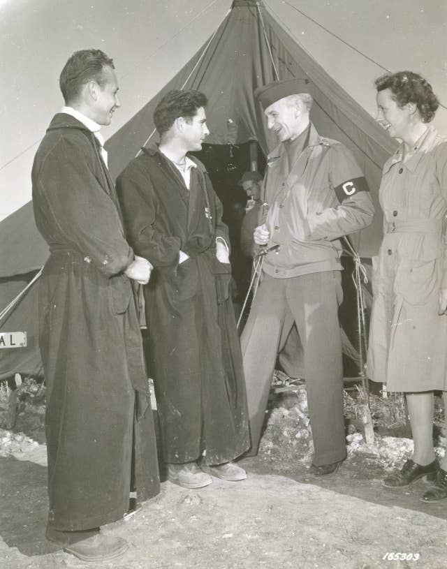 Correspondent, Ernie Pyle, of Scripps-Howard Newspapers, Washington DC, interviewing Sgt. Ralph Gower (of Sacramento, CA), Pvt. Raymond Astrackon (left, of New York City), and 2nd. Lt. Annette Heaton, ANC (of Detroit, MI), attached to an evacuation hospital. North Africa / Date: December 2, 1942.