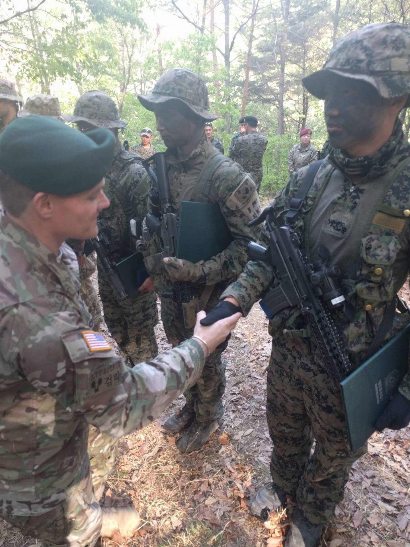 The commander of 2nd Battalion, 1st Special Forces Group, presents his battalion coin and congratulates a soldier from the Republic of Korea Special Forces.