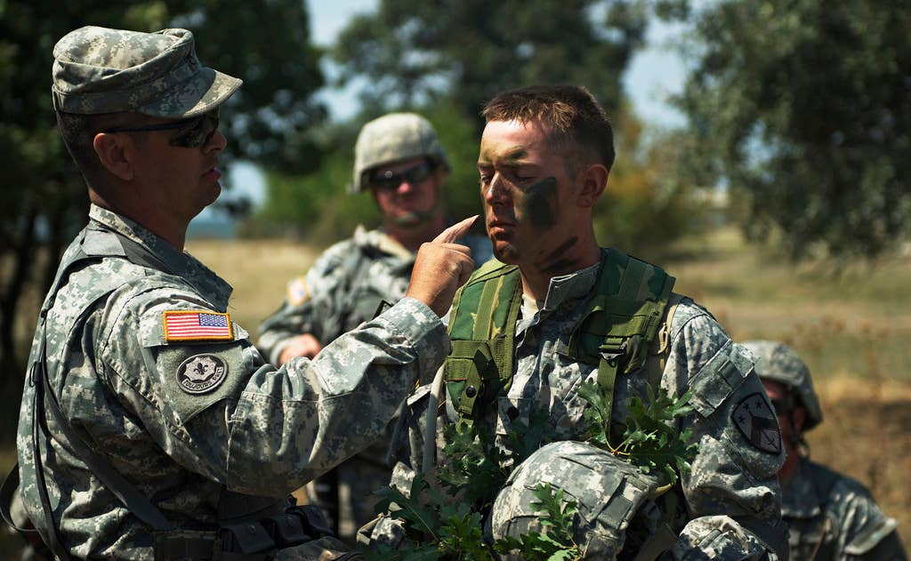 Soldiers of the Tennessee Army National Guard demonstrate how to properly apply camouflage concealment to the face at Babadag Training Area in eastern Romania