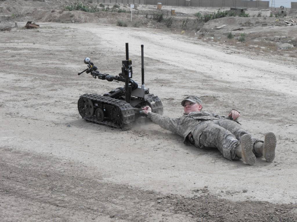 While being dragged, 225th Engineer Brigade Soldier Sgt. Kasandra Deutsch of Pineville, La., demonstrates the power of the Talon robot.