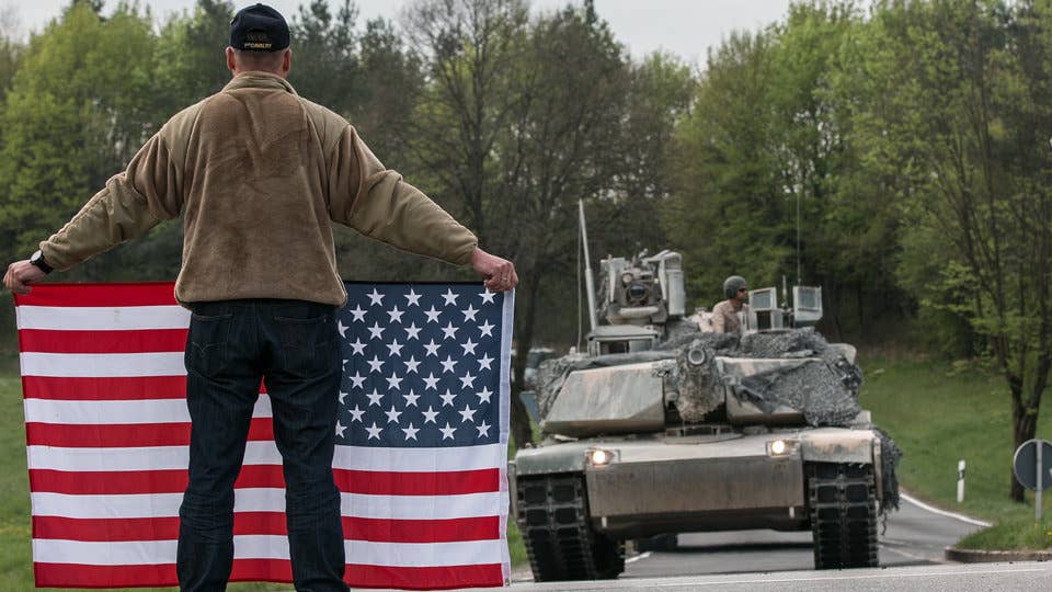 A German man with an US flag greets vehicles from the 2nd Armored Brigade Combat Team, 1st Infantry Division in Germany, April 23, 2018.
