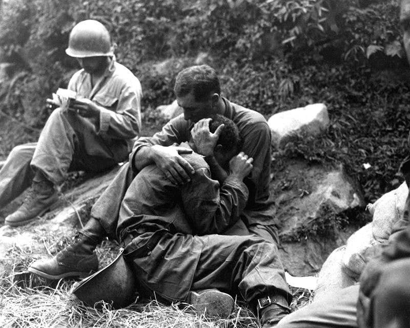 A grief stricken American infantryman whose buddy has been killed in action is comforted by another soldier. Haktong-ni area, Korea. August 28, 1950.