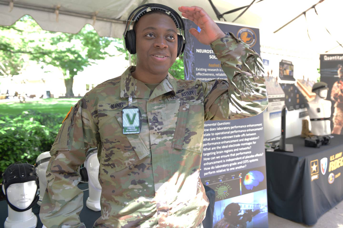 Staff Sgt. Christian King-Lincoln tries on a headset that is providing neurostimulation from a wireless transmitter behind him. The stimulation is not going through his ear pads, but instead through an array of small flexible inducers along the adjustable headband.