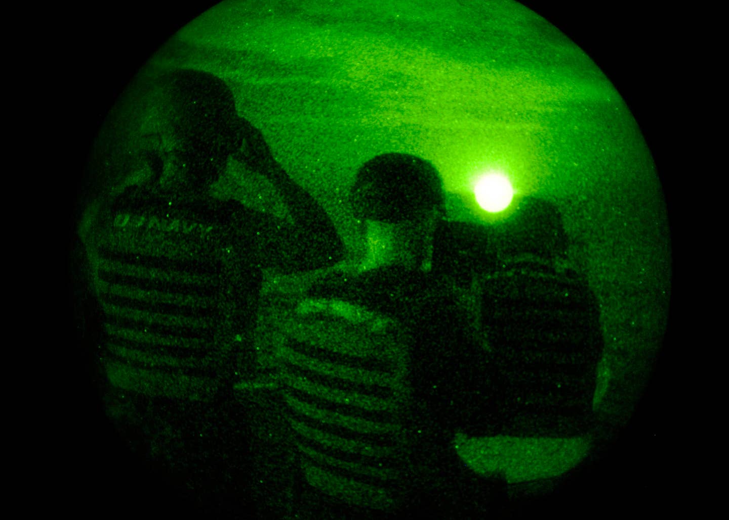 Aviation Ordnanceman Airman Kishawn Tucker peers through night vision binoculars.