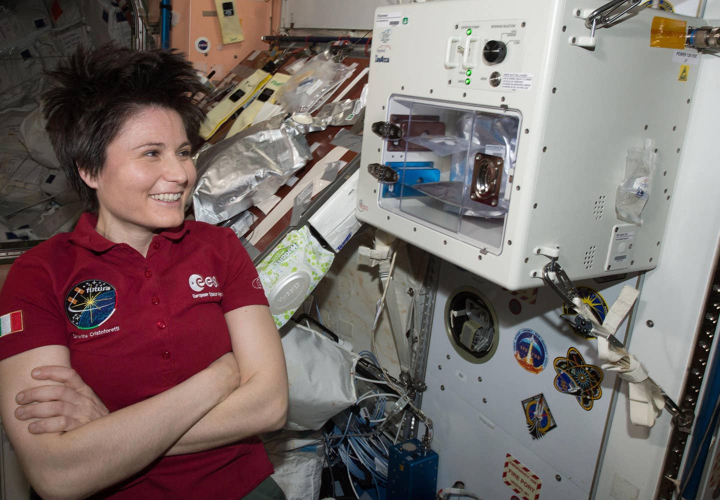European Space Agency Astronaut Samantha Cristoforetti waits next to the newly installed ISSpresso machine. The espresso device allows crews to make tea, coffee, broth, or other hot beverages.