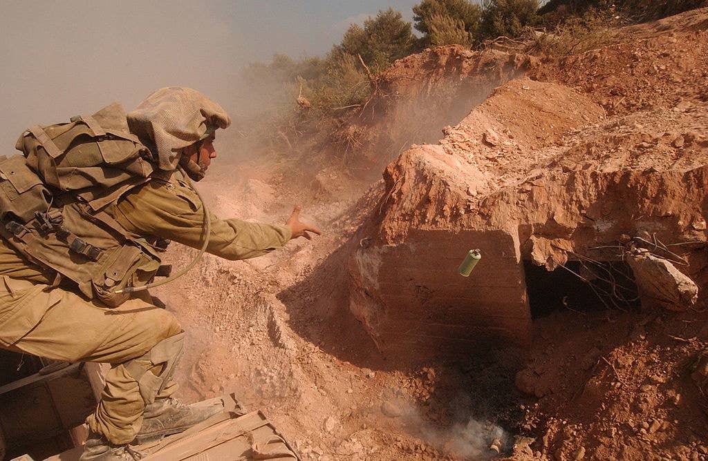 An Israeli soldier tosses a grenade into a Hezbollah bunker.