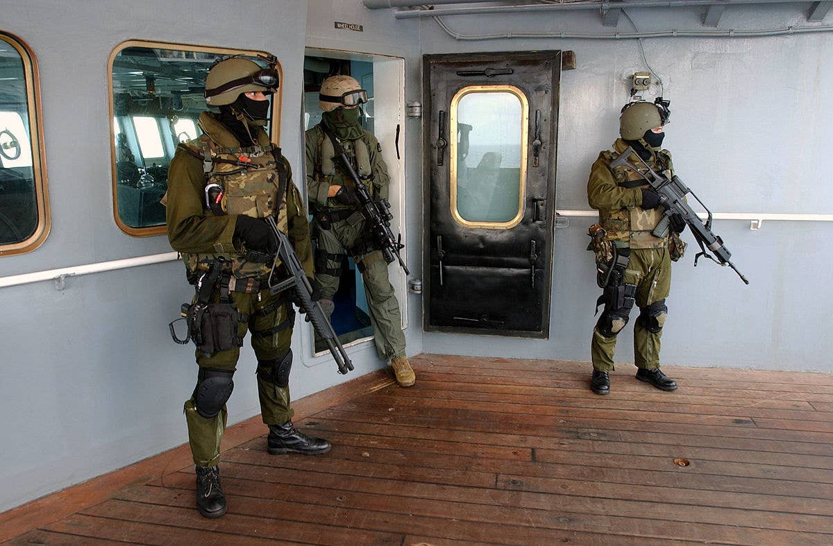 spanish sof stand on a ship in uniforms with weapons drawn as part of an exercise