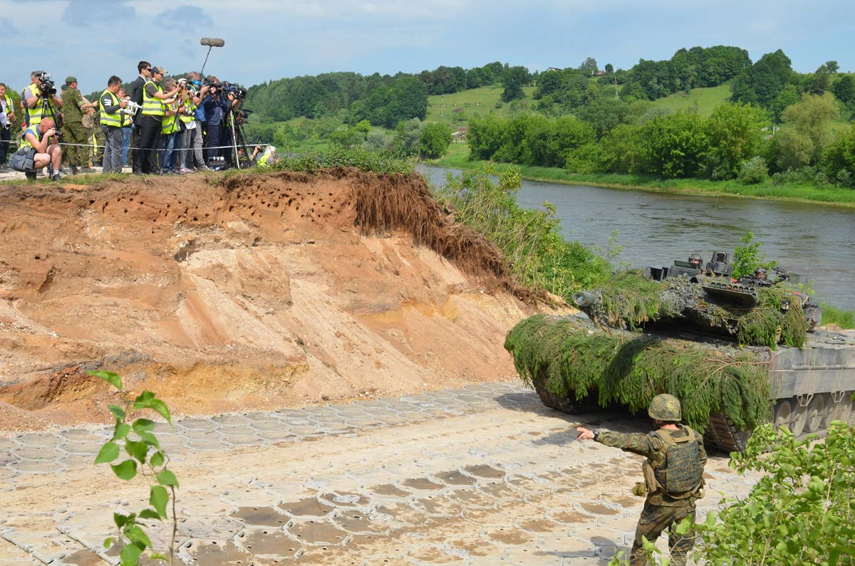 A German Army Soldier directs military vehicles onto land during one of the largest combined exercises in Lithuania, the Suwalki Gap River Crossing, as media observe the event, June 20, 2017.<br>(U.S. Army Sgt. Shiloh Capers)