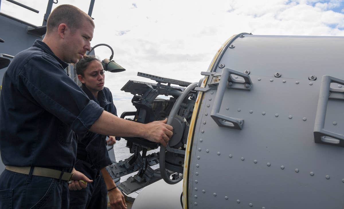 Chief Fire Controlman Ryan Pavelich and Fire Controlman 2nd Class Robin Norris inspect the closed-in weapons system on the USS Wayne E. Meyer.<br>(U.S. Navy Mass Communication Specialist 3rd Class Kelsey L. Adams)