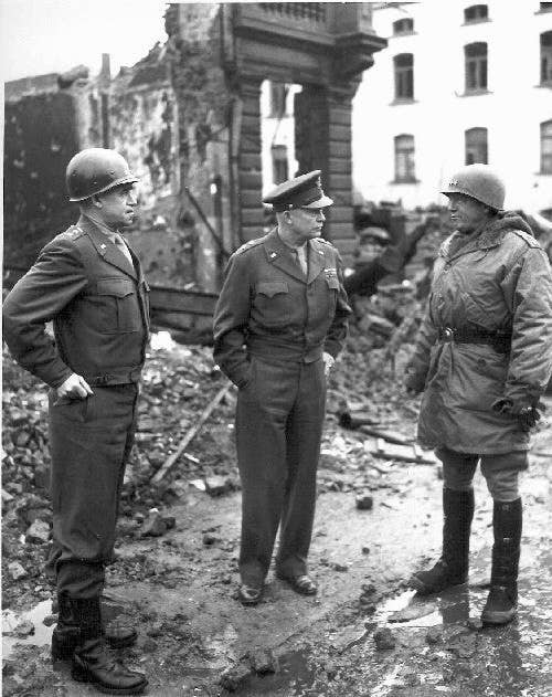 Lieutenant Generals George S. Patton and Omar Bradley talk with Gen. Dwight D. Eisenhower in Bastogne, Belgium, in 1944.<br>(U.S. Army)
