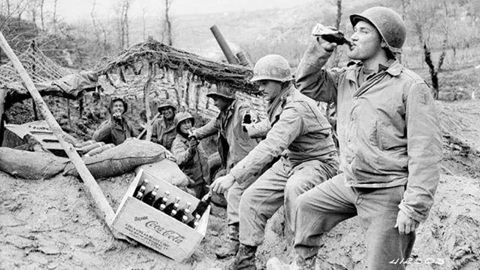 Men of the 133rd Field Artillery Battalion enjoy Cokes on the front, March 17, 1944. Records of the Office of the Chief Signal Officer. Photo courtesy of the <a href="https://prologue.blogs.archives.gov/2015/06/08/the-coca-cola-bottle-celebrating-100-years-of-an-american-icon/" target="_blank" rel="noreferrer noopener">National Archives</a>.